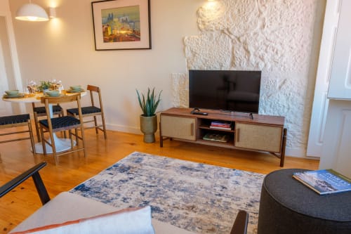 Sala de estar moderna na AgapeStay Porto B&B com móveis de madeira, TV, área de jantar e parede de tijolo aparente