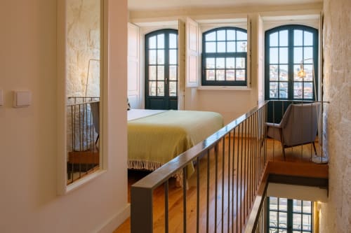Quarto mezanino na AgapeStay Porto com cama de casal, janelas com vista para a cidade e guarda-corpos de madeira
