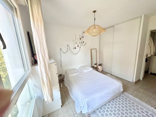 Chambre lumineuse au Mas Des Cigales De Lambesc, Aix-en-Provence, avec lit blanc, luminaires suspendus et vue sur la ville