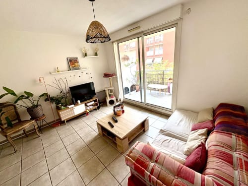 Lumineux appartement citadin à Aix-en-Provence avec canapé confortable, téléviseur, mobilier en bois et vue sur balcon