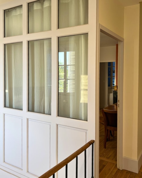 Vérière Kipling avec portes vitrées, rampe d'escalier en bois et vue sur l'élégant appartement du Château de Sampigny