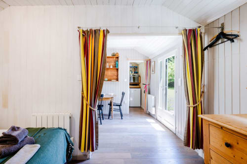 Intérieur lumineux du gîte Locations Montjoïa Provence avec rideaux rayés, mobilier en bois et espace ouvert