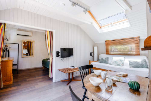 Intérieur spacieux du gîte Locations Montjoïa Provence avec lit, coin repas, TV et lucarne à Le Thor