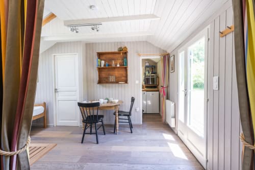 Intérieur lumineux du gîte Locations Montjoìa Provence avec salle à manger, étagères en bois et vues sur le jardin