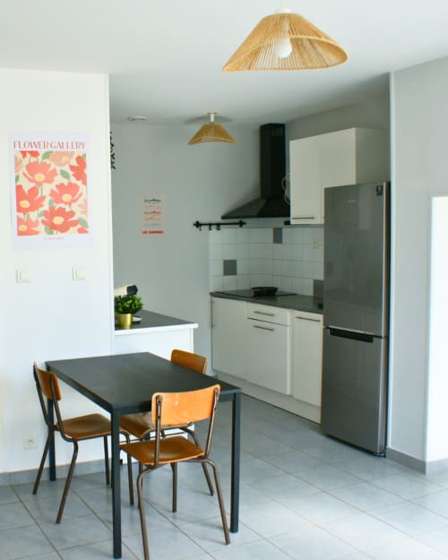 Cuisine-salle à manger contemporaine à Kipling House avec chaises en bois, table noire, armoires blanches, électroménagers inox