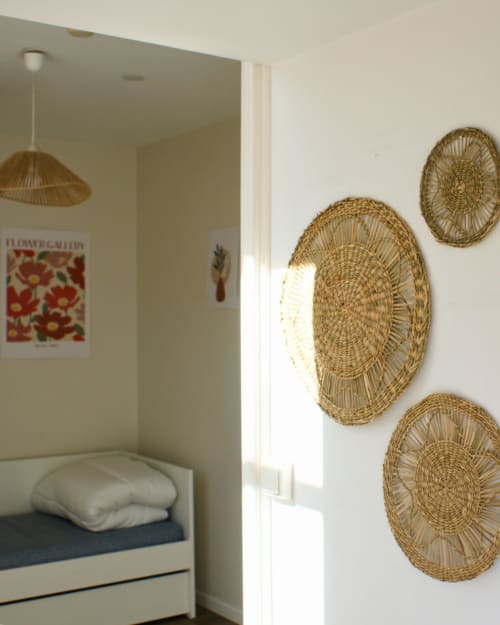 Chambre à Kipling House avec paniers tressés au mur, lit à oreiller blanc et lampe suspendue.