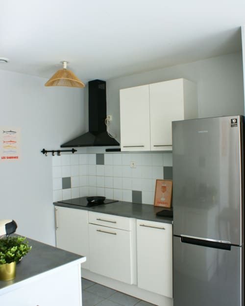 Cuisine moderne à Kipling House avec armoires blanches, plan de travail noir, réfrigérateur acier inoxydable et hotte noire
