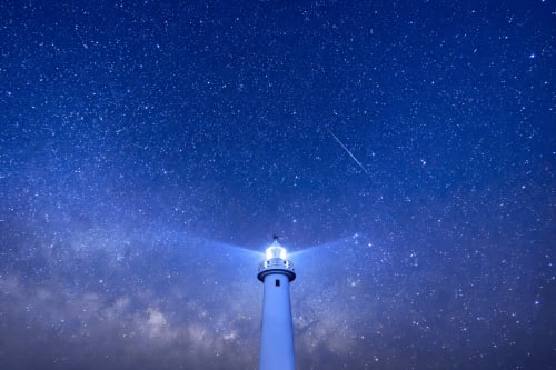 Il fascio del faro che perfora il cielo notturno stellato vicino a Grosseto, Italia