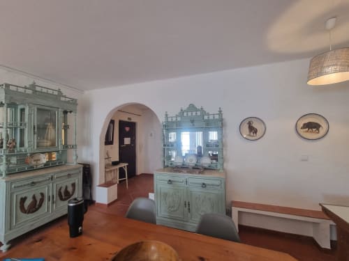 Elegante sala de estar do apartamento Solazur Ericeira com móveis vintage turquesa, lareira e decoração costeira