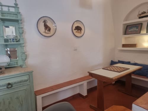 Interior do apartamento em Ericeira com mesa de xadrez, armário turquesa, arte animal emoldurada e prateleiras em nicho arqueado