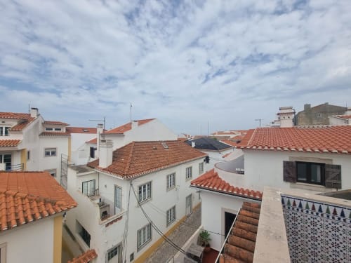 Vista do telhado de Ericeira com edifícios brancos e telhados de barro vermelho, apartamento Solazur