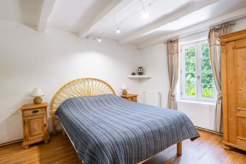 Chambre lumineuse du gîte Le Gîte bleu au Thor, Provence, avec lit en bois, vue sur jardin et mobilier bois