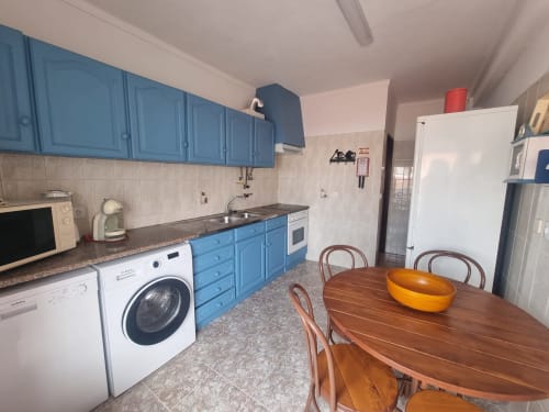 Cozinha azul com mesa de jantar em madeira no apartamento Solazur em Ericeira, Portugal