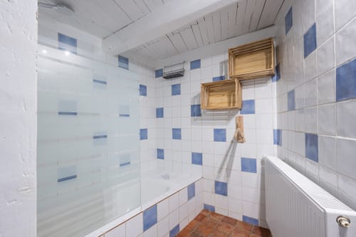 Salle de bains du gîte Le Gîte bleu à Le Thor, Provence, avec carrelage à carreaux bleus et blancs et douche vitrée