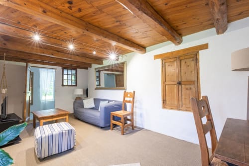 Salon chaleureux du gîte Le Gîte bleu à Locations Montjoïa Provence, Le Thor, avec poutres, canapé bleu et jardin