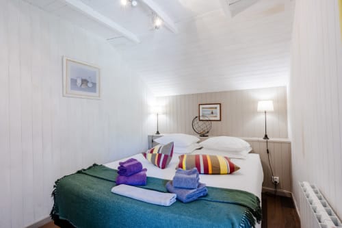 Chambre de la maison d'hôtes Le Gîte bleu à Locations Montjoìa Provence avec coussins colorés, linge blanc et vue sur le jardin