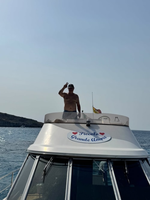 Uomo a torso nudo su barca bianca 