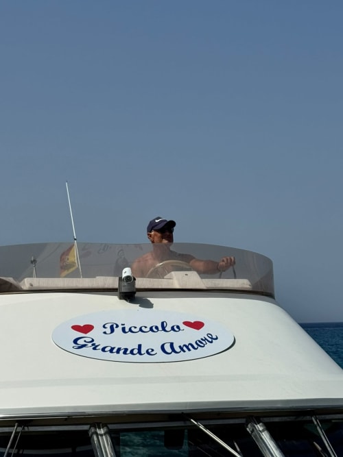 Uomo sulla barca Piccola Grande Amore a Lampedusa, Italia con mare e cielo azzurro cristallino