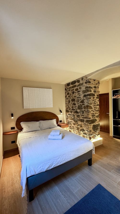 Camera moderna presso il B&B Talking Stones a Dolceacqua con muro in pietra, letto in legno e vista sulla città