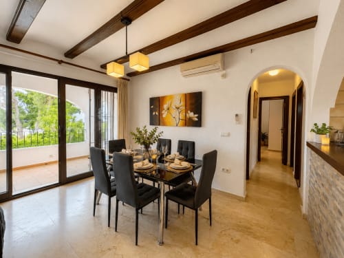 Comedor moderno en villa Casa Jonur, Moraira, con mesa negra, sillas oscuras y vistas a la terraza