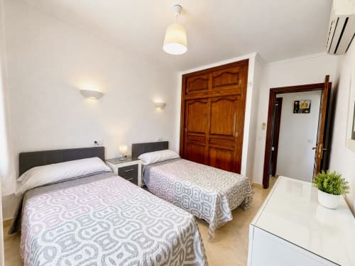 Dormitorio doble en villa Casa Jonur, Moraira, con dos camas individuales, iluminación moderna y puertas de armario de madera