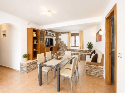 Comedor moderno con muebles de madera, detalles en ladrillo y vistas al océano en la villa Casa Jonur en Moraira