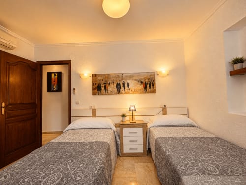 Habitación doble en villa Casa Jonur, Moraira con dos camas, mesita de noche, cuadros decorativos e iluminación cálida