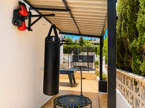 Zona de entrenamiento en la terraza de una villa con saco de boxeo y trampolín con vistas a la piscina en Moraira
