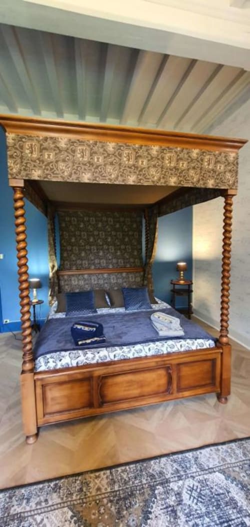 Lit à baldaquin quatre colonnes avec cadre bois et ciel patterné bleu dans la chambre du Manoir de Saint-Ouen
