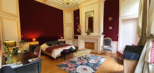 Chambre Supérieure au Manoir de Saint-Ouen avec lit king-size, cheminée, murs bordeaux, parquet et vue sur le jardin