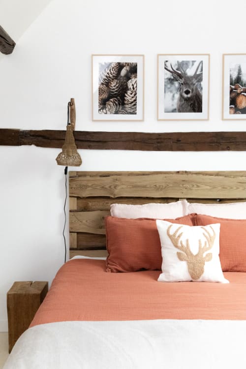 Chambre rustique aux Lodges de la Ferme de la Chaise avec lit en bois, parure corail et photographies animalières encadrées.