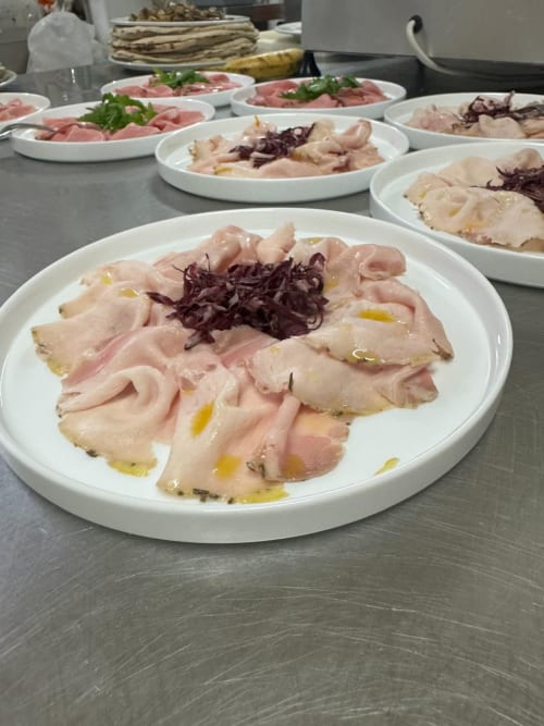 Sliced cured meats and seafood arranged on white plates at Hotel Ristorante alle Querce in Castelbuono
