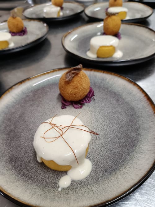 Plated dessert at Hotel Ristorante alle Querce in Castelbuono featuring golden pastry, white cream, and purple garnish