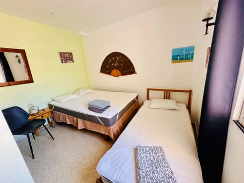 Dormitorio compartido en Nerja Holiday Homes con dos camas, paredes amarillas, ventilador decorativo, silla y mobiliario apto para niños