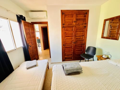 Dormitorio espacioso en apartamento Nerja Holiday Homes con dos camas, puertas de madera, aire acondicionado y ventana en Nerja, España