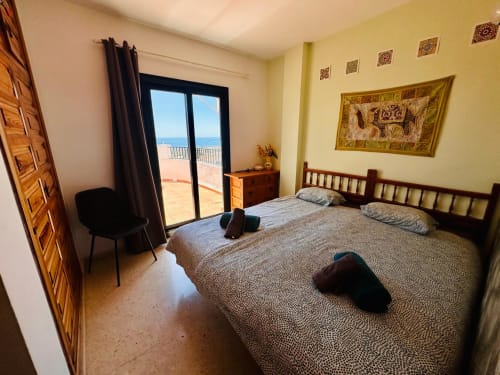 Dormitorio luminoso en apartamento de Nerja Holiday Homes con terraza con vistas al mar, cama doble, muebles de madera y paredes amarillas