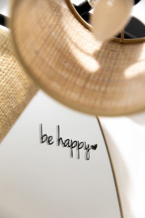 Note manuscrite « soyez heureux » avec cœur sur carte blanche près d'un coussin texturé beige au Lodges de la Ferme de la Chaise