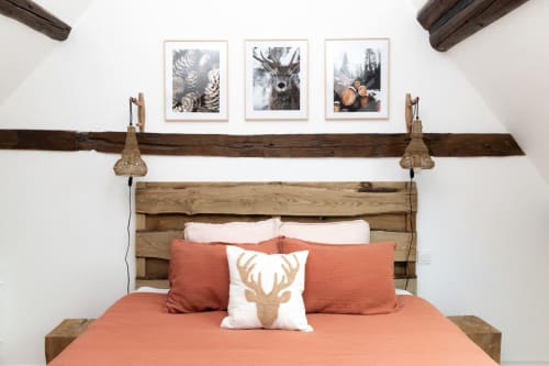 Chambre rustique aux Lodges de la Ferme de la Chaise avec tête de lit en bois, literie corail et tableaux de faune