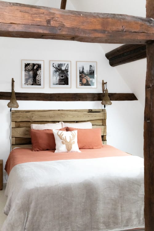 Chambre rustique aux Lodges de la Ferme de la Chaise avec poutres en bois, décoration cerf et literie corail