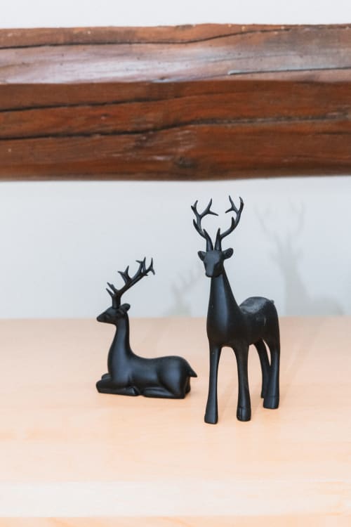 Figurines de cerfs noirs exposées sur étagère en bois dans la chambre Cerf des Lodges de la Ferme de la Chaise