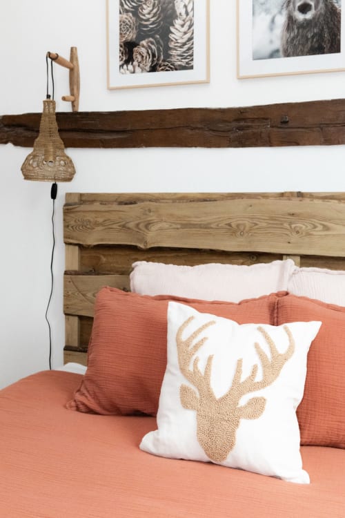 Lit rustique en bois avec oreillers corail et coussin motif cerf aux Lodges de la Ferme de la Chaise, Saint-Antonin-de-Sommaire