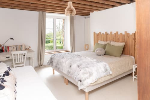 Chambre lumineuse avec lit en bois, vue sur le jardin, bureau et poutres apparentes rustiques aux Lodges de la Ferme de la Chaise