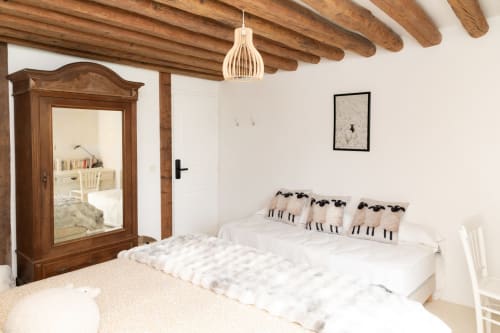 Chambre lumineuse aux Lodges de la Ferme de la Chaise avec poutres apparentes, lit queen-size avec coussins motif mouton