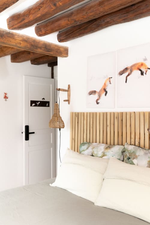 Chambre confortable aux Lodges de la Ferme de la Chaise avec poutres apparentes, tête de lit en bois et tableaux de renards sur murs blancs