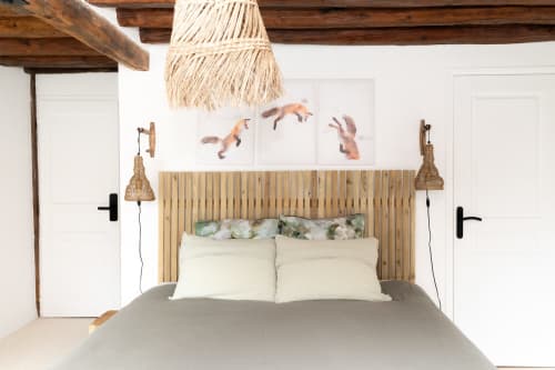 Chambre confortable aux Lodges de la Ferme de la Chaise avec tête de lit en bois, literie crème, luminaires suspendus tissés et tableau de renard