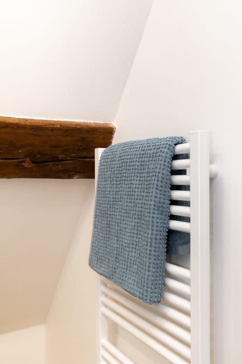 Serviette bleue texturée drapiée sur sèche-serviettes blanc dans la Chambre Goupil aux Lodges de la Ferme de la Chaise