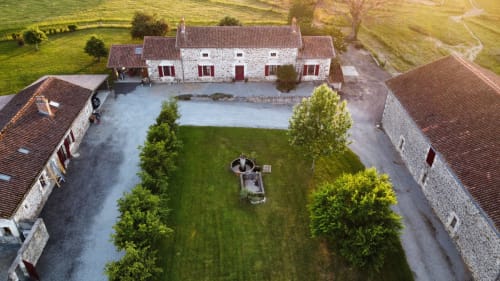 Aerial view of Domaine de Beau Site cottage with manicured gardens, courtyard, and stone buildings in Peyrat-de-Bellac