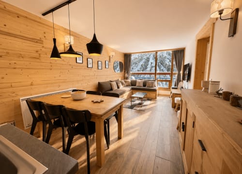 Intérieur d'appartement moderne en bois avec table à manger, canapé et vue sur les montagnes à Cosyarc Bourg-Saint-Maurice