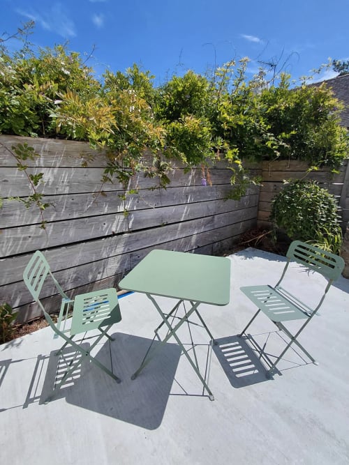 Coin repas ensoleillé du gîte Kerguerc'h, Belle Île en Mer, avec table et chaises vertes