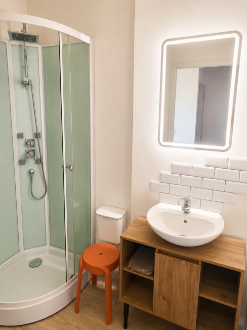 Modern bathroom in Le Grand Gîte cottage at Domaine de Beau Site with shower, wooden vanity, and LED mirror